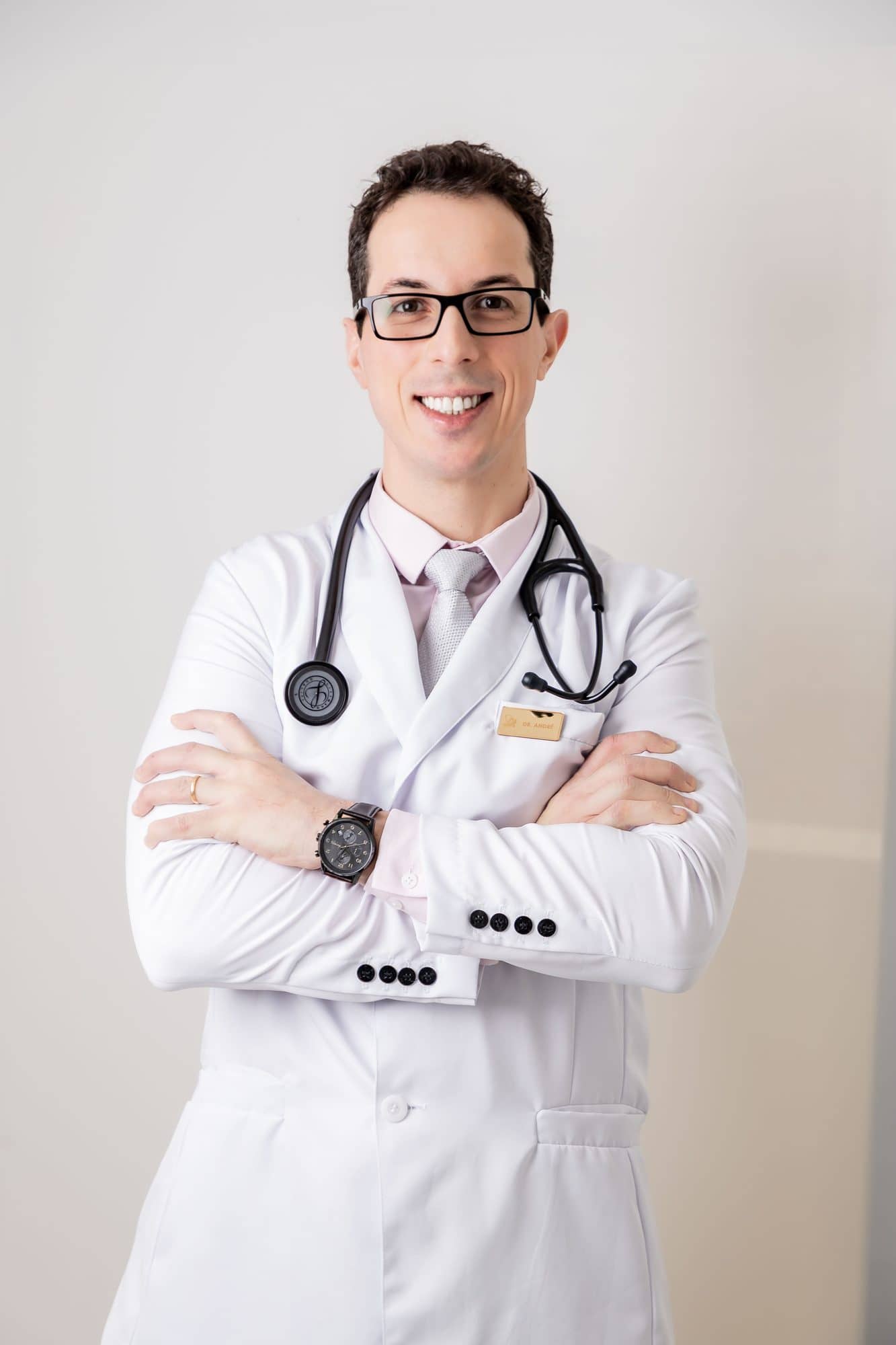 Dr. André Andrade, nutrólogo e cardiologista, de jaleco e estetoscópio, sorrindo de braços cruzados
