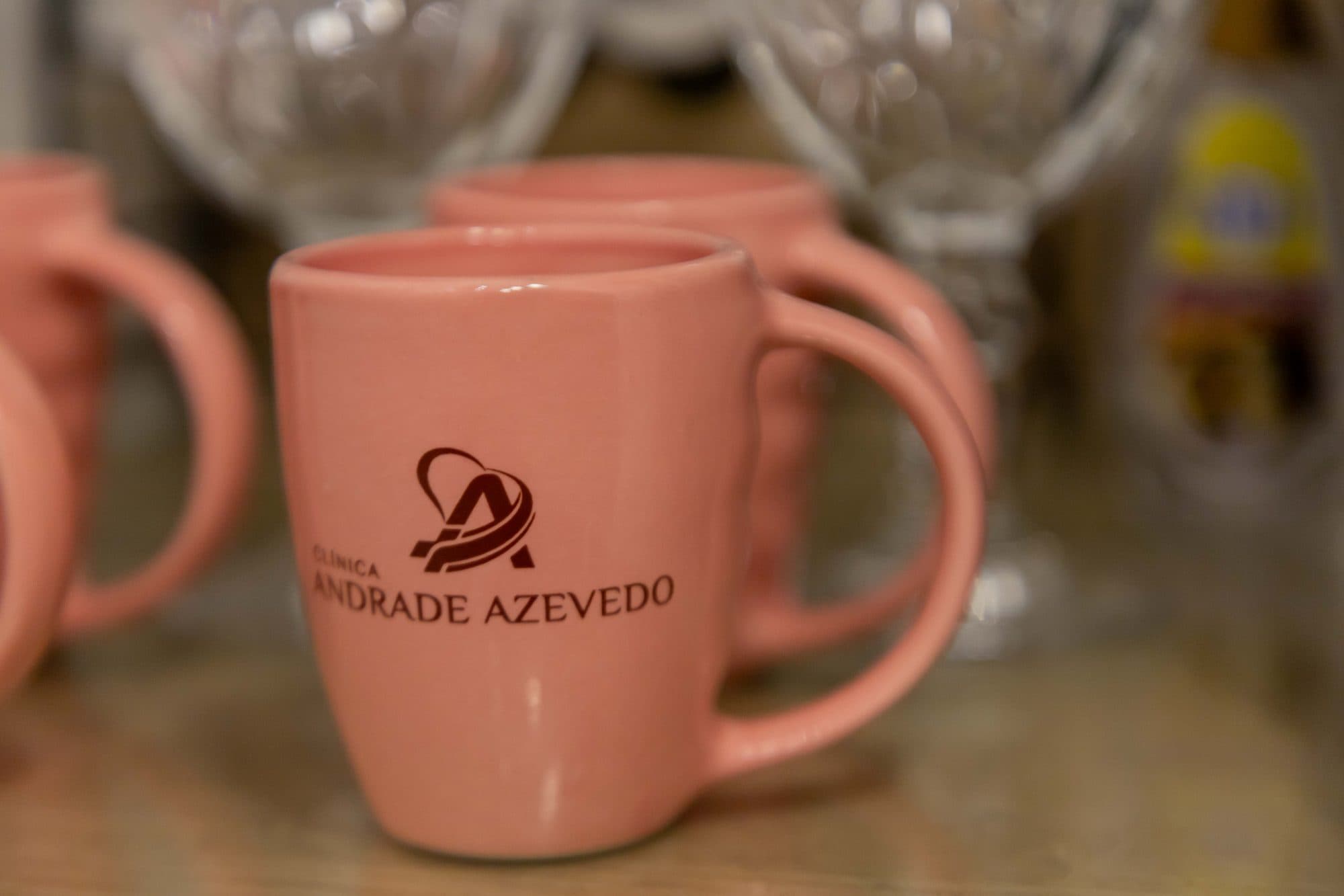 Caneca rosa com a logo da clínica sobre o balcão do café